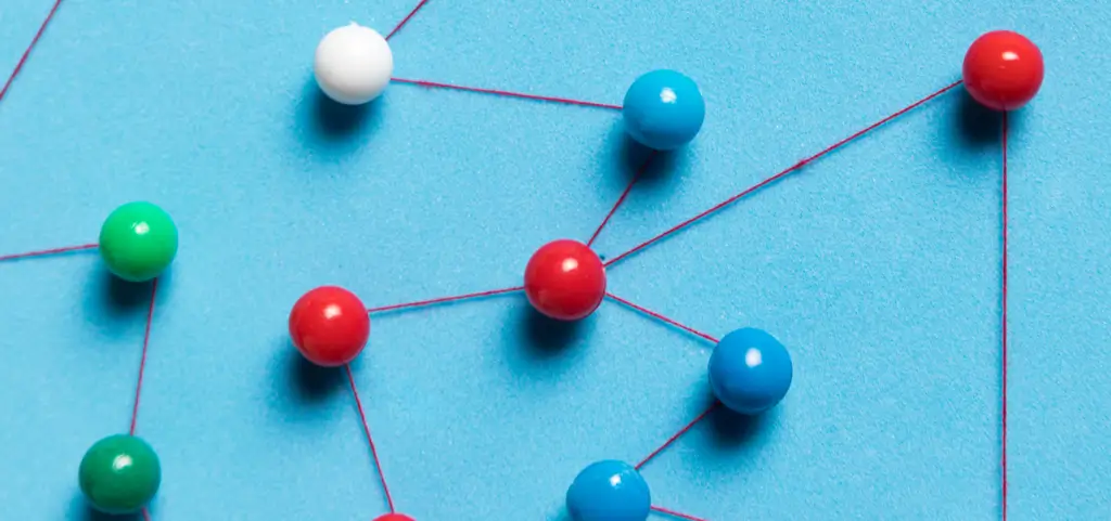 Coloured pushpins on a blue board joined by red thread into a network of points and paths