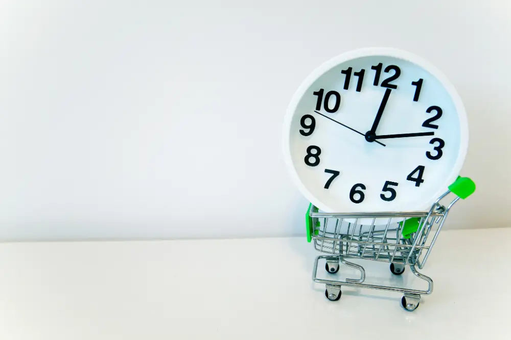 A white alarm clock sitting in a miniature shopping cart