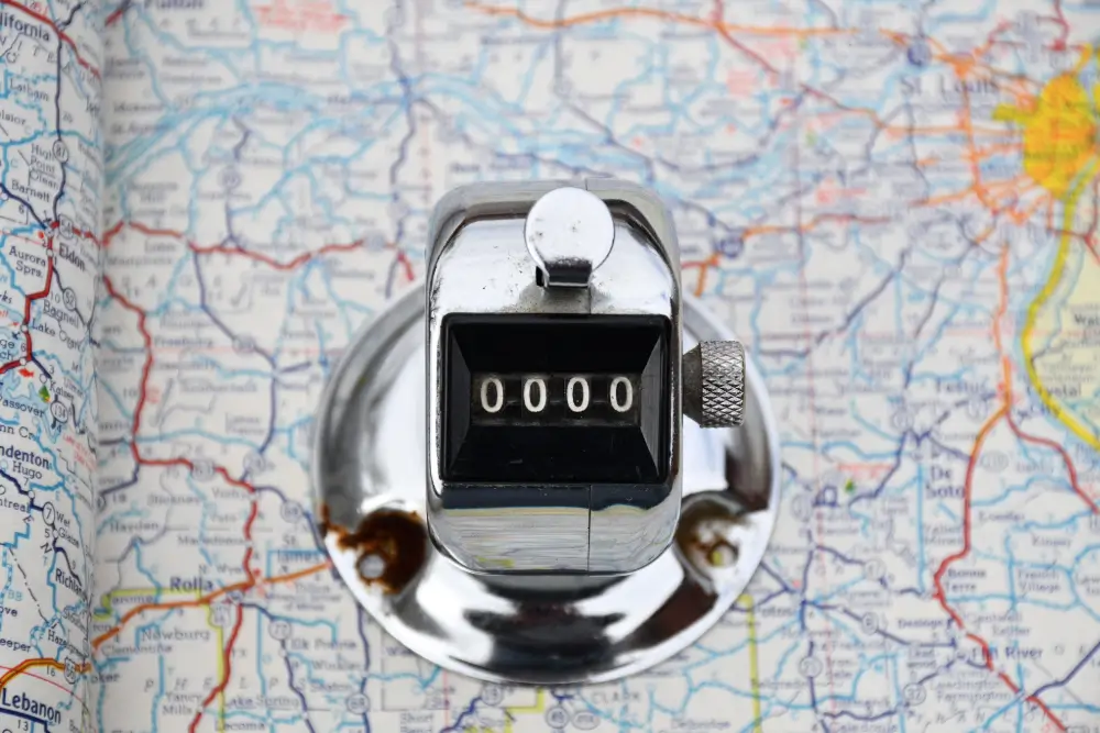 A chrome tally counter reading 0000 resting on a road atlas